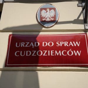 Czerwona tabliczka na budynku: urząd do spraw cudzoziemców
