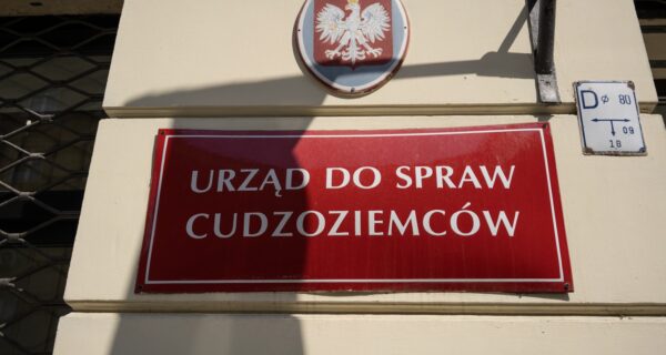 Czerwona tabliczka na budynku: urząd do spraw cudzoziemców