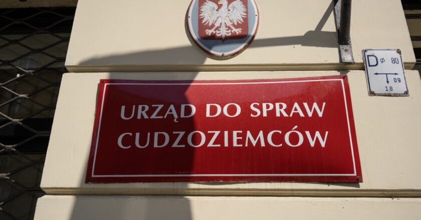 Czerwona tabliczka na budynku: urząd do spraw cudzoziemców