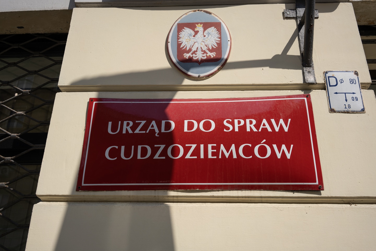 Czerwona tabliczka na budynku: urząd do spraw cudzoziemców