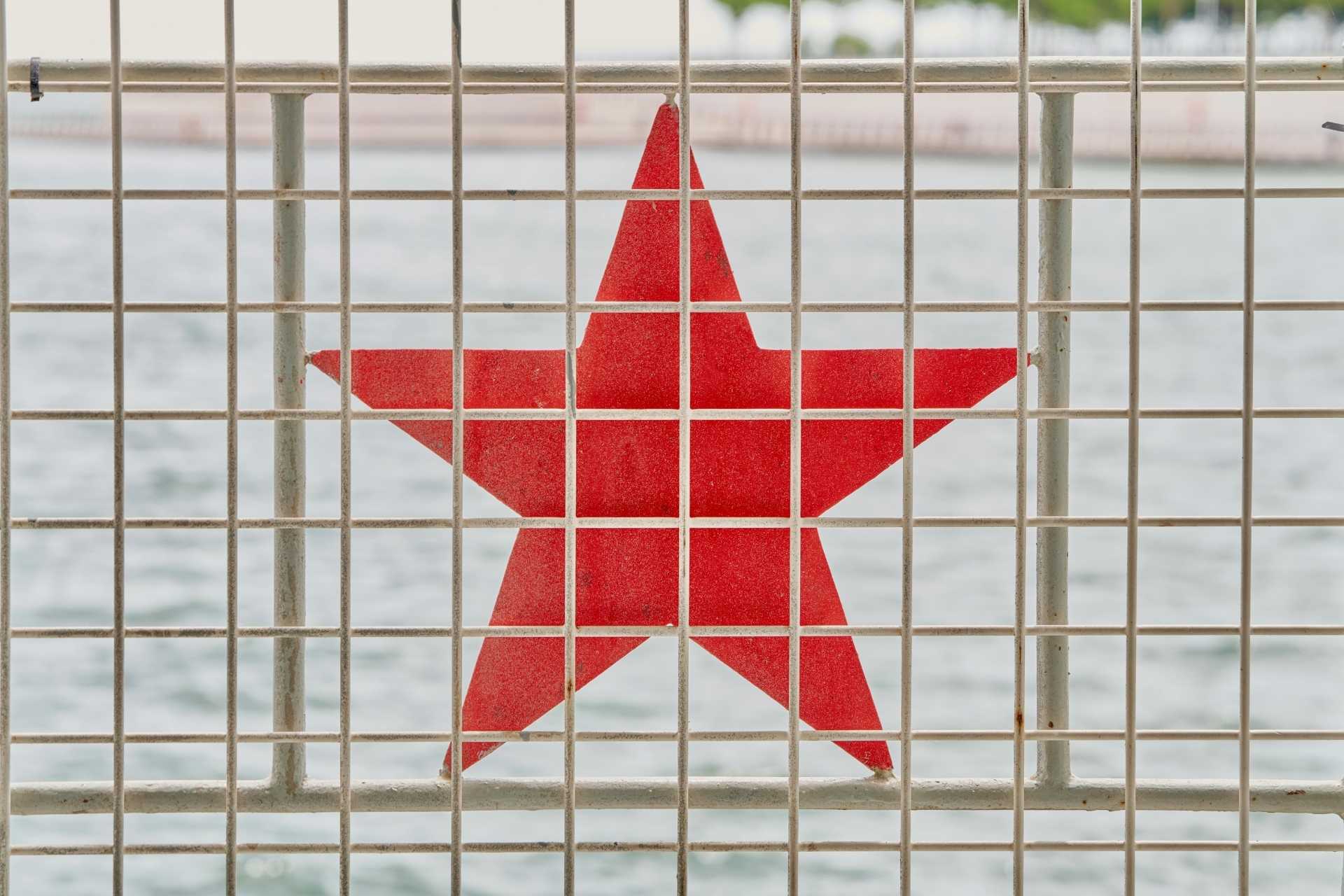 Czerwona gwiazda za kratami przypominającymi więzienne