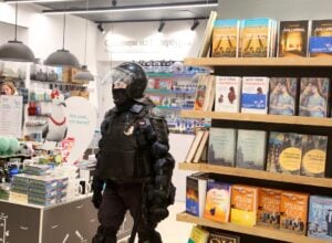 Policjant w petersburskiej księgarni próbuje zatrzymać młodą kobietę biorącą udział w antywojennych protestach przeciwko agresji na Ukrainę.