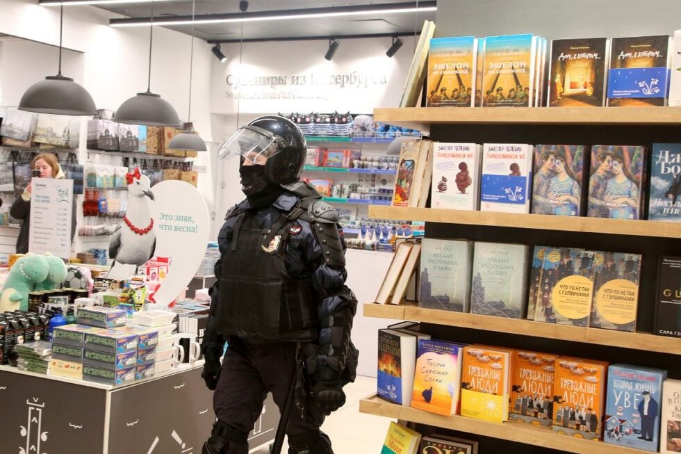 Policjant w petersburskiej księgarni próbuje zatrzymać młodą kobietę biorącą udział w antywojennych protestach przeciwko agresji na Ukrainę.