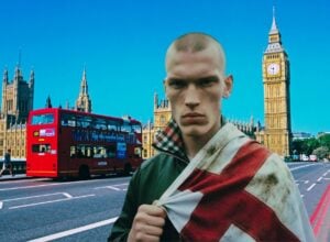 Danny Bones na tle Londynu, za jego plecami widać piętrowy czerwony autobus i Big Bena