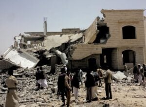 Grupa ludzi ogląda ruiny budynku trafionego rakietą