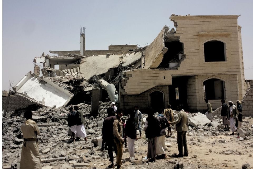 Grupa ludzi ogląda ruiny budynku trafionego rakietą