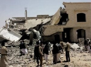 Grupa ludzi ogląda ruiny budynku trafionego rakietą