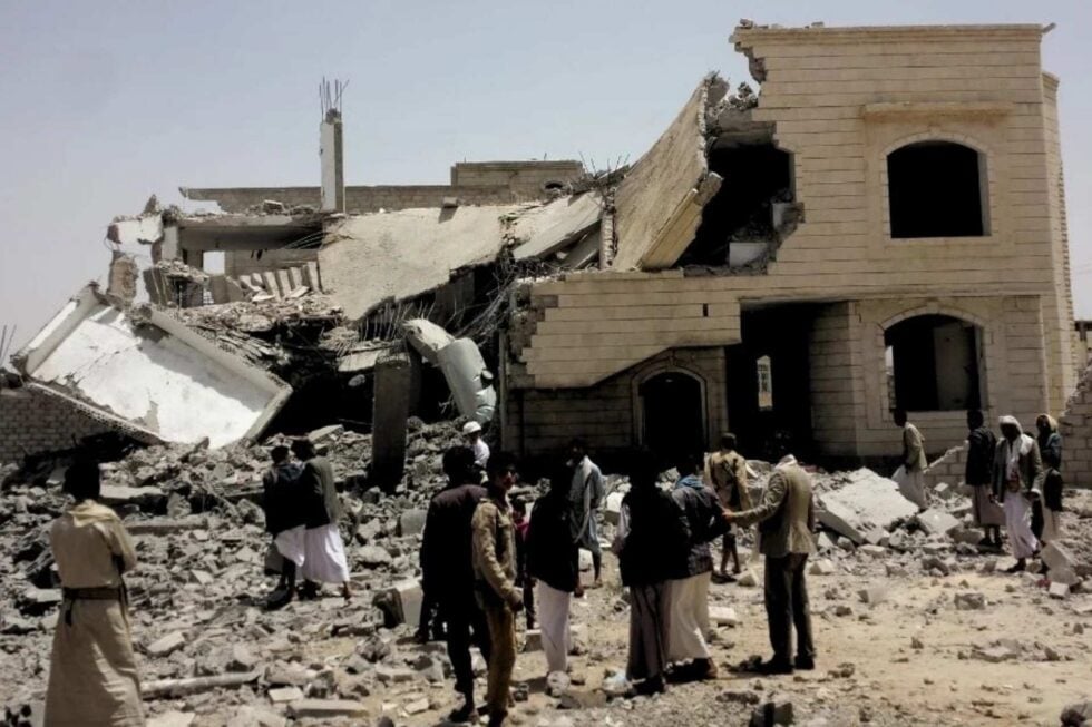 Grupa ludzi ogląda ruiny budynku trafionego rakietą