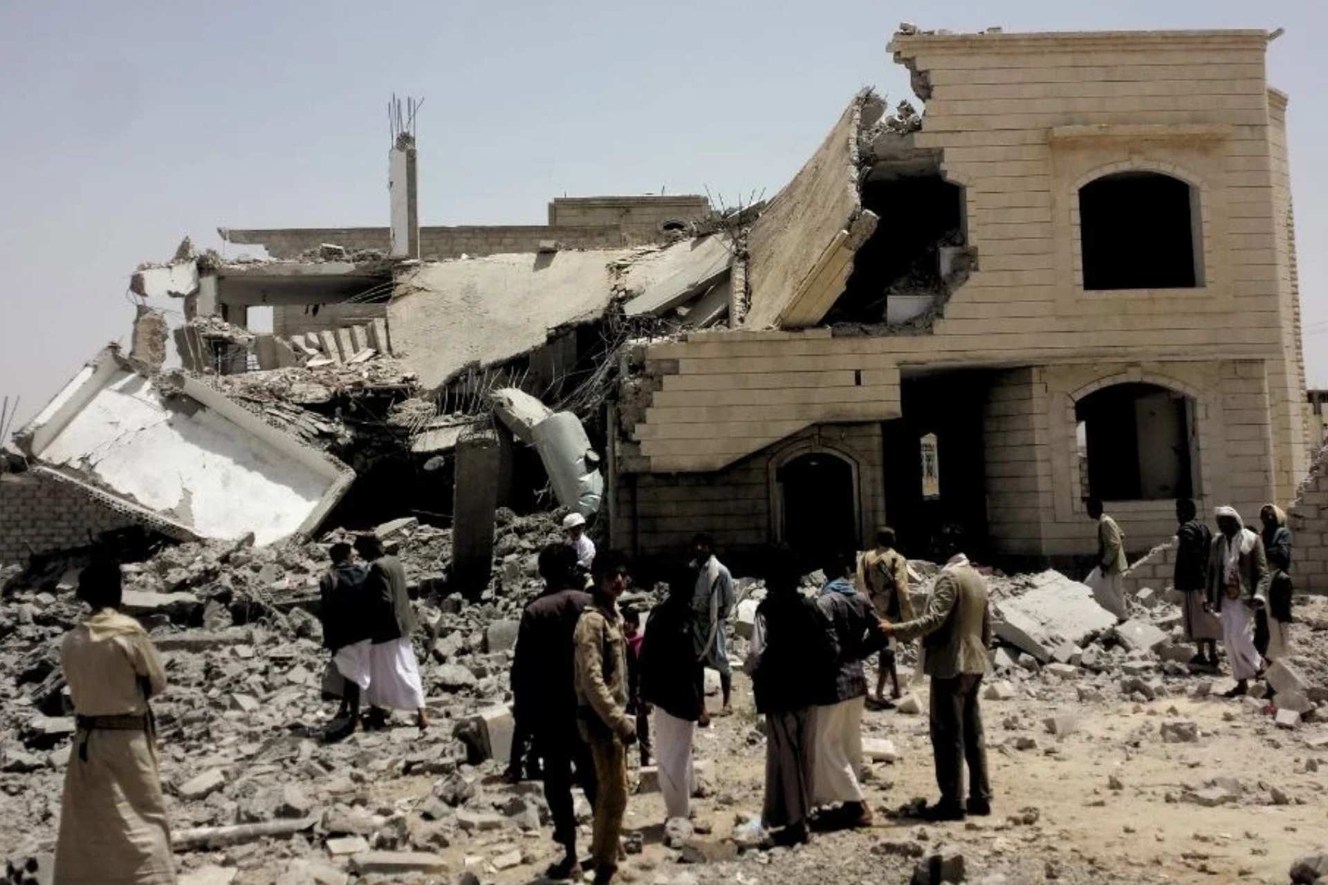 Grupa ludzi ogląda ruiny budynku trafionego rakietą