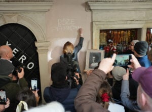 Osoba pisze na murze w Zamościu, napis Różę Pamiętamy