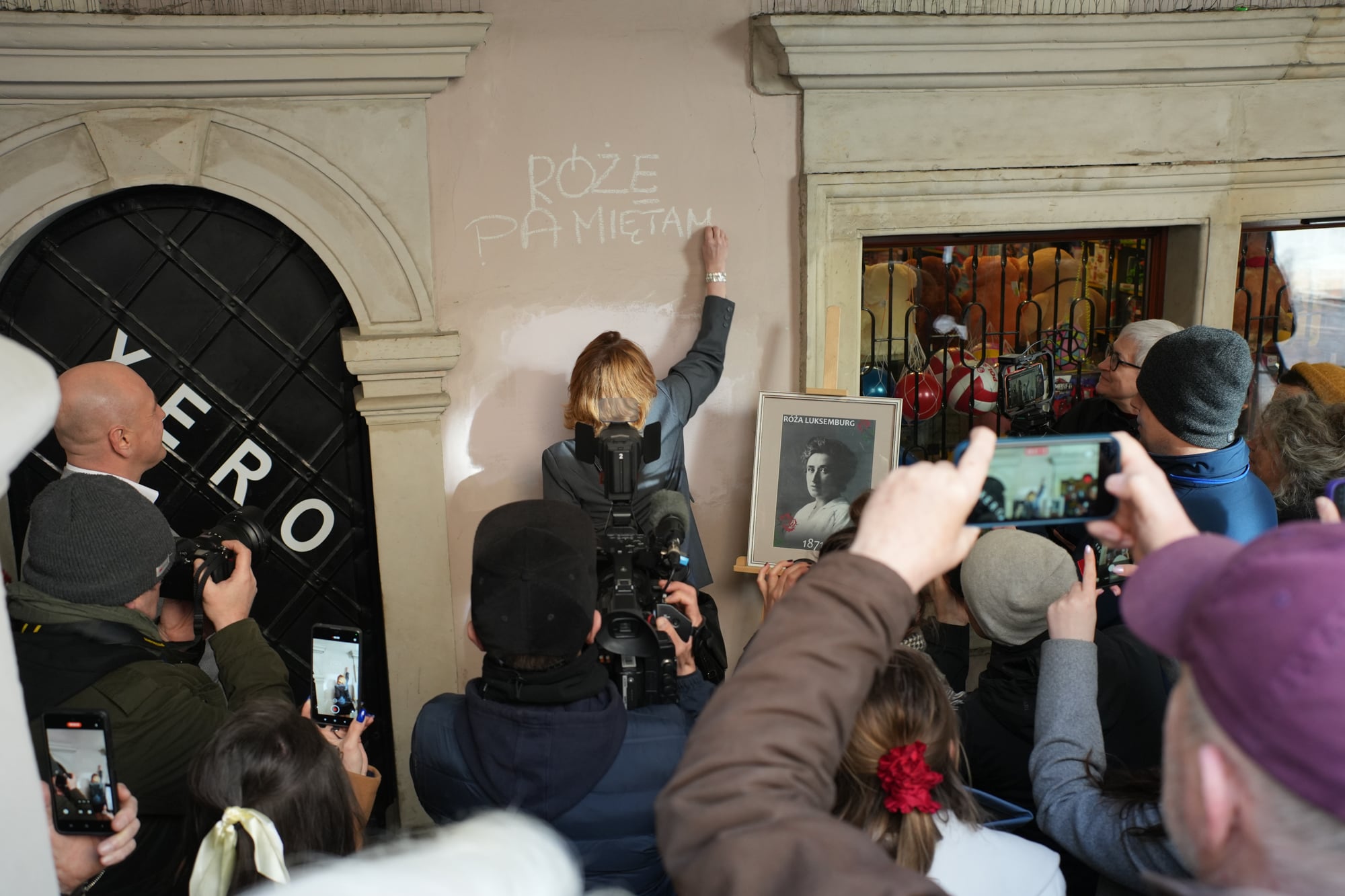 Osoba pisze na murze w Zamościu, napis Różę Pamiętamy
