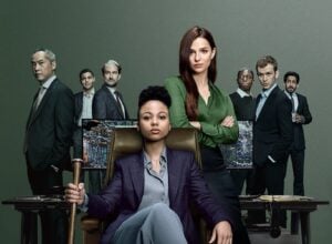 Plakat serialu Branża - grupa ludzi stoi za siedzącą w fotelu główną bohaterką