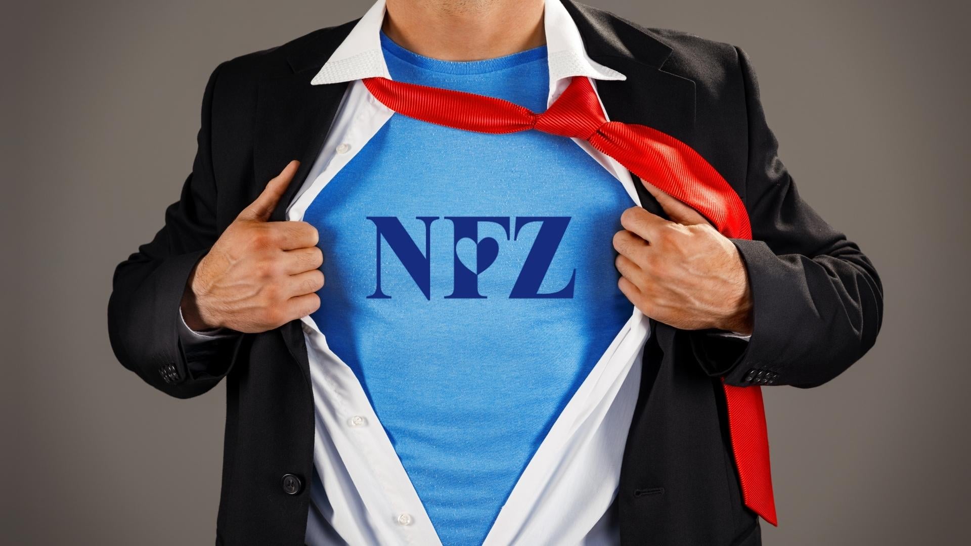 Postać superbohatera widoczna od pasa do szyi, rozchylająca koszulę i pokazująca bluzkę z napisem NFZ