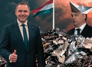 Po lewej stronie uśmiechnięty Karol Nawrocki pokazujący kciuka do góry, za nim złomowisko z wetkniętą flagą Węgier, z prawej strony Viktor Orban w kapeluszu z papierowego samolotu