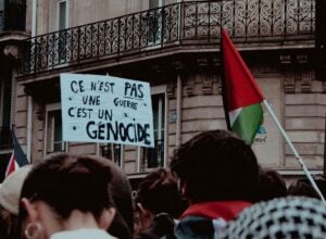 Tłum na propalestyńskiej demonstracji, na środku widoczny baner z hasłem „Ce n’est pas une guerre, c’est un génocide"