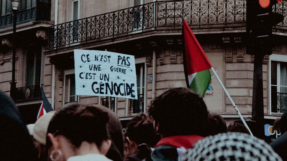 Tłum na propalestyńskiej demonstracji, na środku widoczny baner z hasłem „Ce n’est pas une guerre, c’est un génocide"