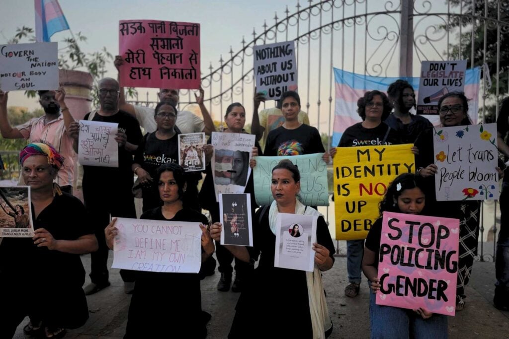 Grupa trzynastu osób LGBT+ unoszących kolorowe transparenty z równościowymi hasłami po angielsku i w hindi