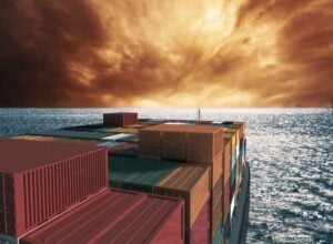 Statek transportowy z kolorowymi kontenerami zmierzający w stronę wzburzonego horyzontu