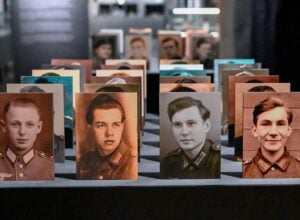 Row of vintage portrait cards of young men in military uniforms lined up on a display table in a museum setting.