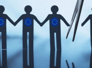 Kontury czterech papierowych ludzików, trzy mają na sobie flagę UE i trzymają się za ręce, czwarta z flagą USA została odcięta od reszty widocznymi nożyczkami