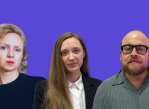 Three professionals posing for a group photo against a purple backdrop: a curly-haired woman on the left, a woman in a blazer center, and a man with glasses on the right, all looking at the camera.