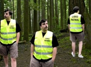 Bartek Skrobisz w odblaskowej kamizelce z napisem "libkopatrol" wklejony potrójnie na tle lasu