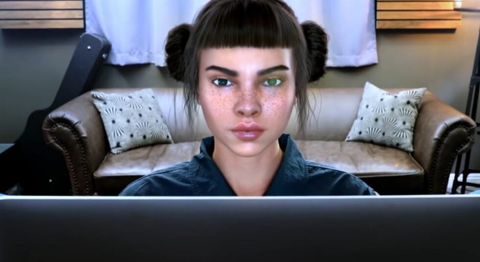 Freckled woman with dark hair in buns, facing a laptop on a couch in a living room area.