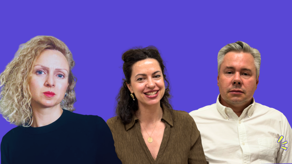 Three adults posing for a team photo against a solid purple background: left a woman with curly blonde hair, center a smiling brunette in a brown blouse, right a man with gray hair in a white shirt.