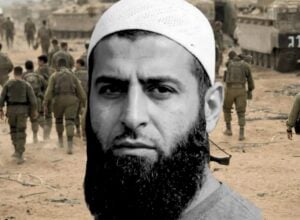 Close-up of a bearded man wearing a white cap, overlaid on a desert battlefield with soldiers walking in the background.