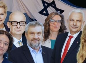 Seven professionally dressed adults posing for a group photo with a large flag featuring a blue Star of David motif in the background.