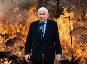 Jarosław Kaczyński przy mikrofonie na tle płonącego lasu (fotomontaż)