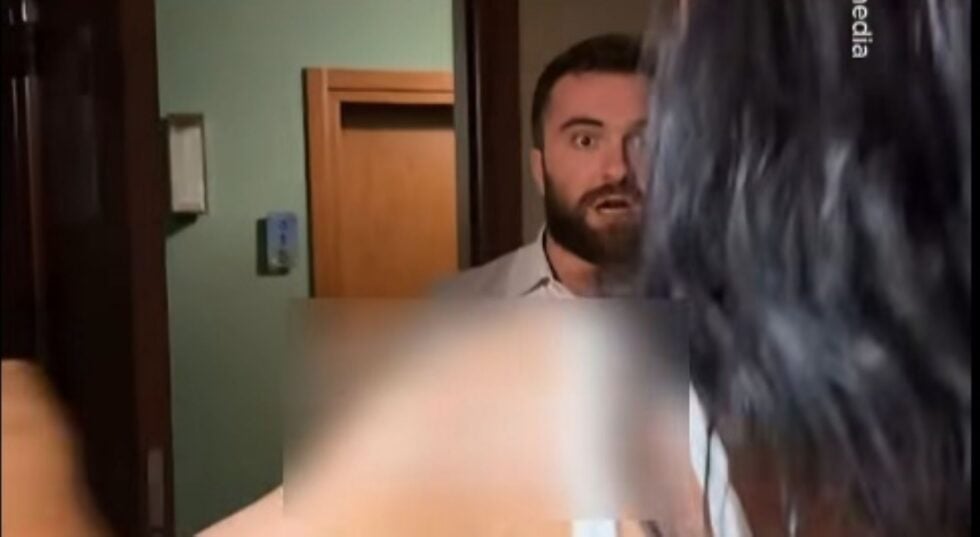 Bearded man in a doorway looking surprised as a blurred figure passes by in a dim hallway.