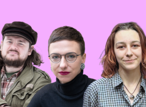 Three adults posing for a photo against a pink background: a bearded man in a cap and olive jacket on the left, a woman with short hair and round glasses in the center, and a woman in a checkered shirt on the right.