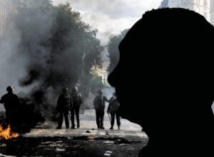 Na pierwszym planie czarny cień Putina, za nim kłęby dymu i policja podczas zamieszek w Paryżu